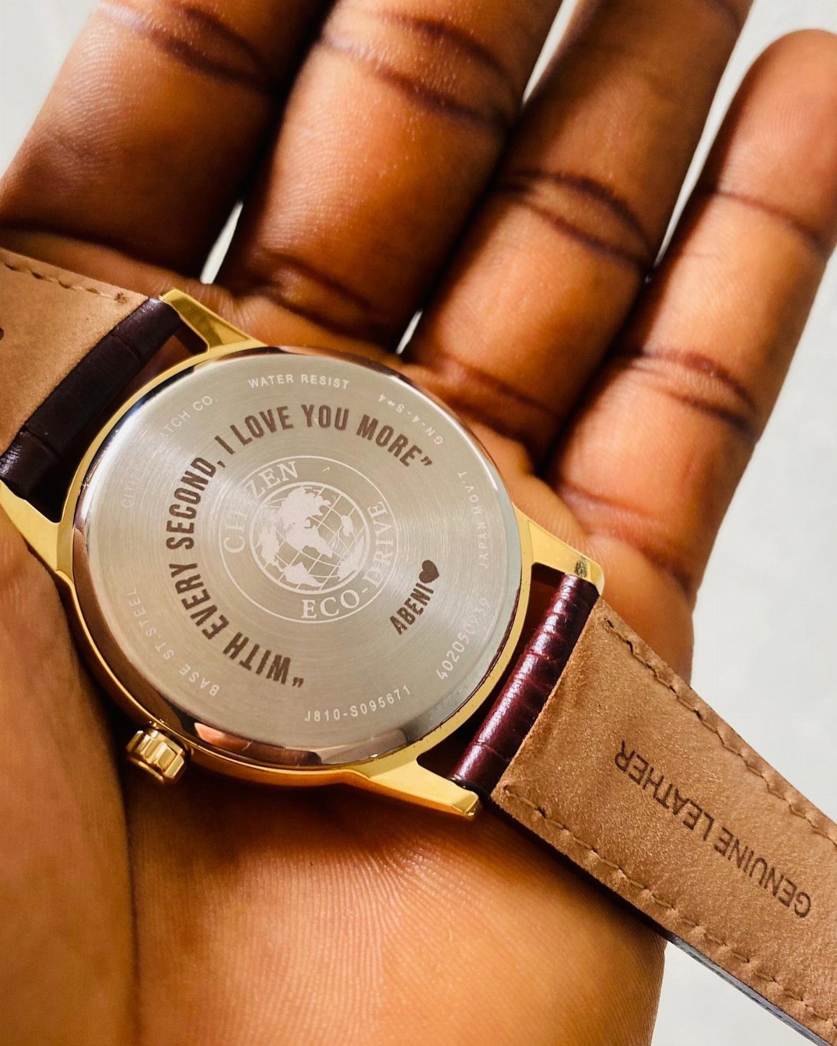 Gold watch with brown leather strap showing engraved personal message on the back