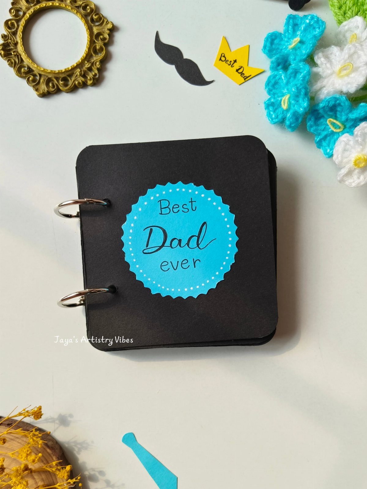 Black ring-bound memory book with Best Dad ever sticker and decorative craft items.
