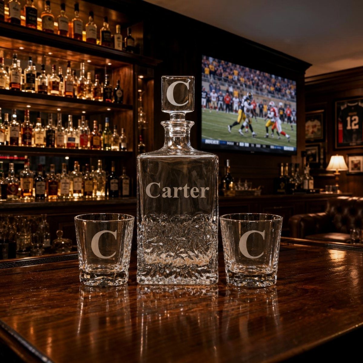 Engraved glass whiskey decanter and two glasses with the name Carter on a bar
