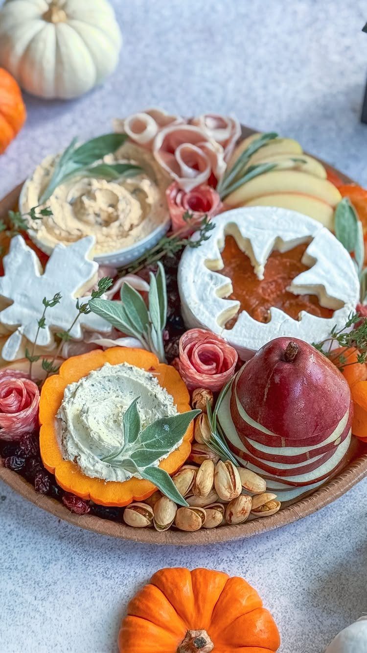 Brie cheese wheel with a leaf cutout filled with jam on a festive board.