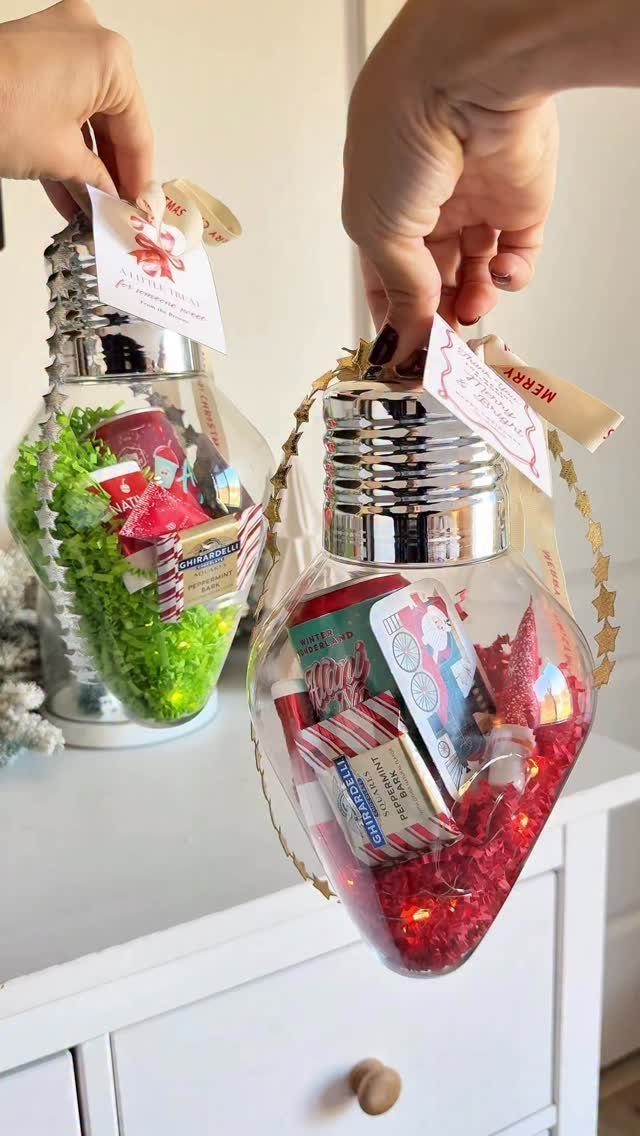 Clear plastic ornaments filled with candies and colorful filler held by two hands.