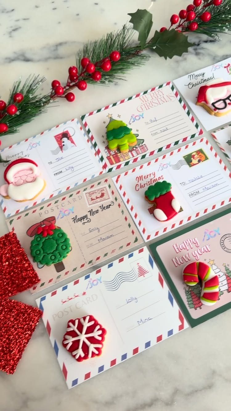 Christmas sugar cookies on decorative postcards with a red berry garland on marble.
