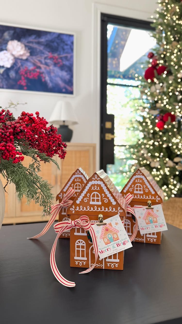 Gingerbread house gift boxes with red striped ribbons on a dark table