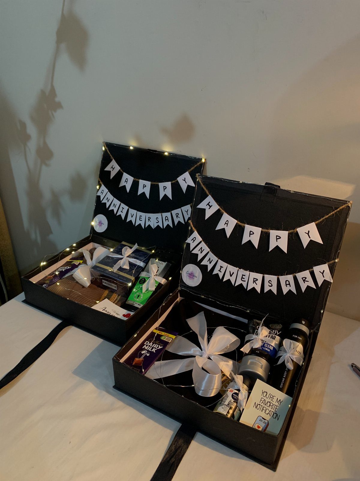 Two black gift boxes filled with treats and anniversary bunting banners on white fabric