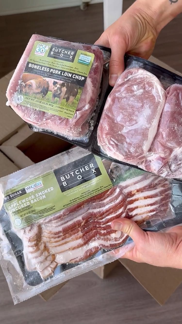 Vacuum-sealed pork chops and bacon packages held over a cardboard delivery box.