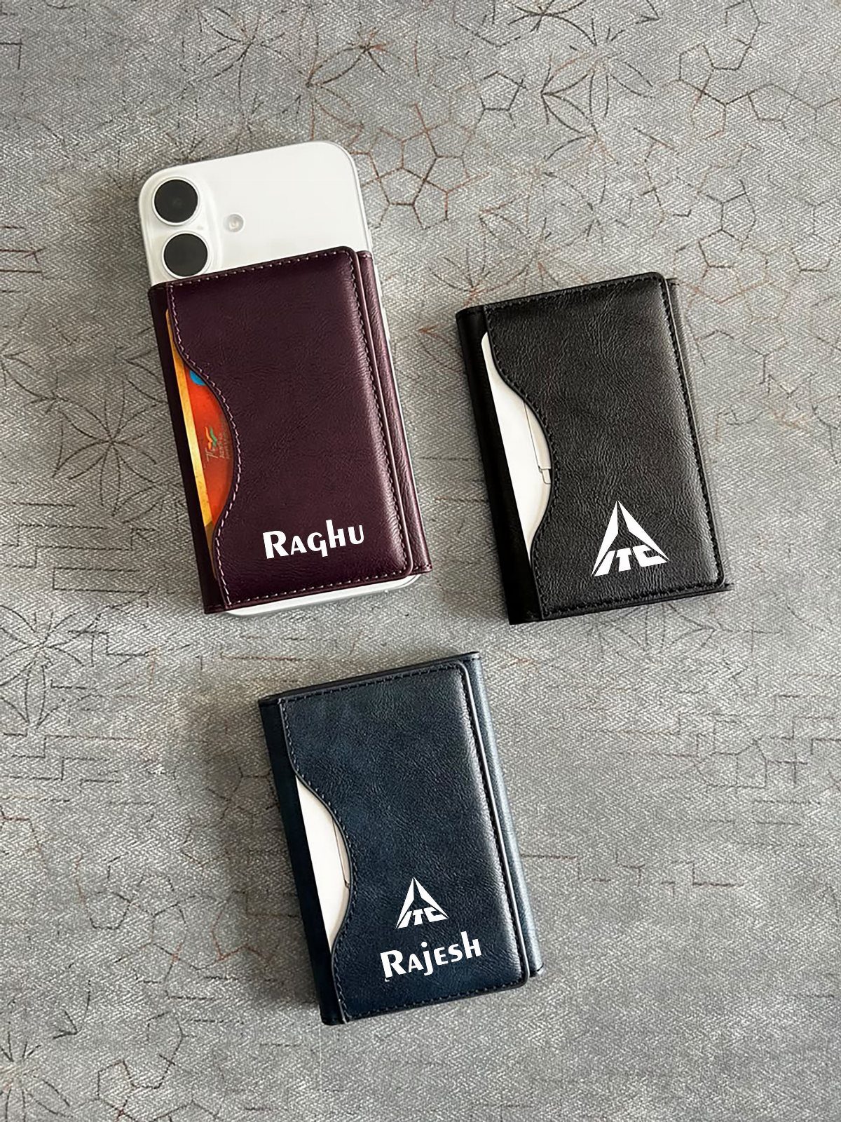 Three personalized leather phone wallet cases in burgundy, black, and navy blue.