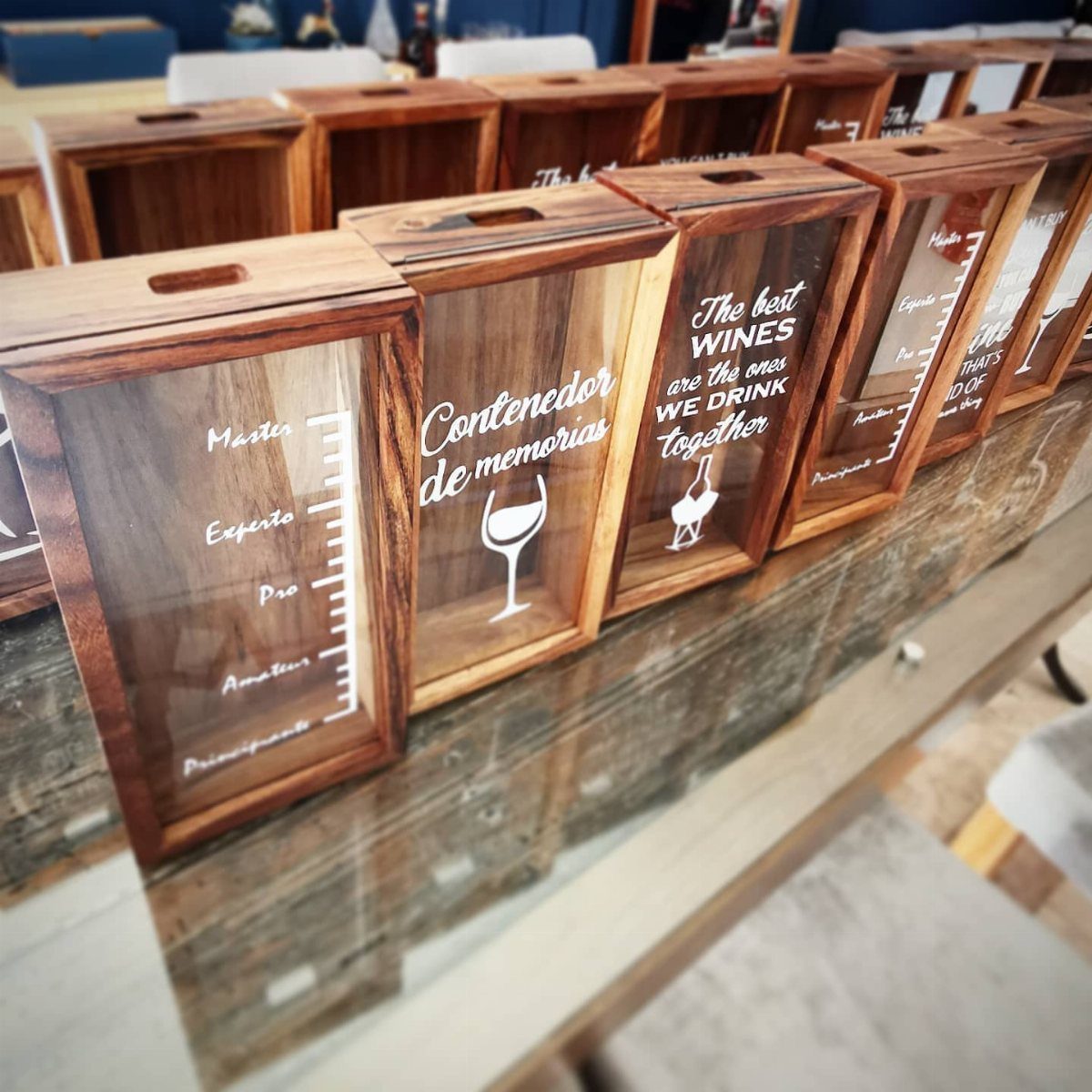 Wooden wine memory boxes with engraved text and glass fronts on a table