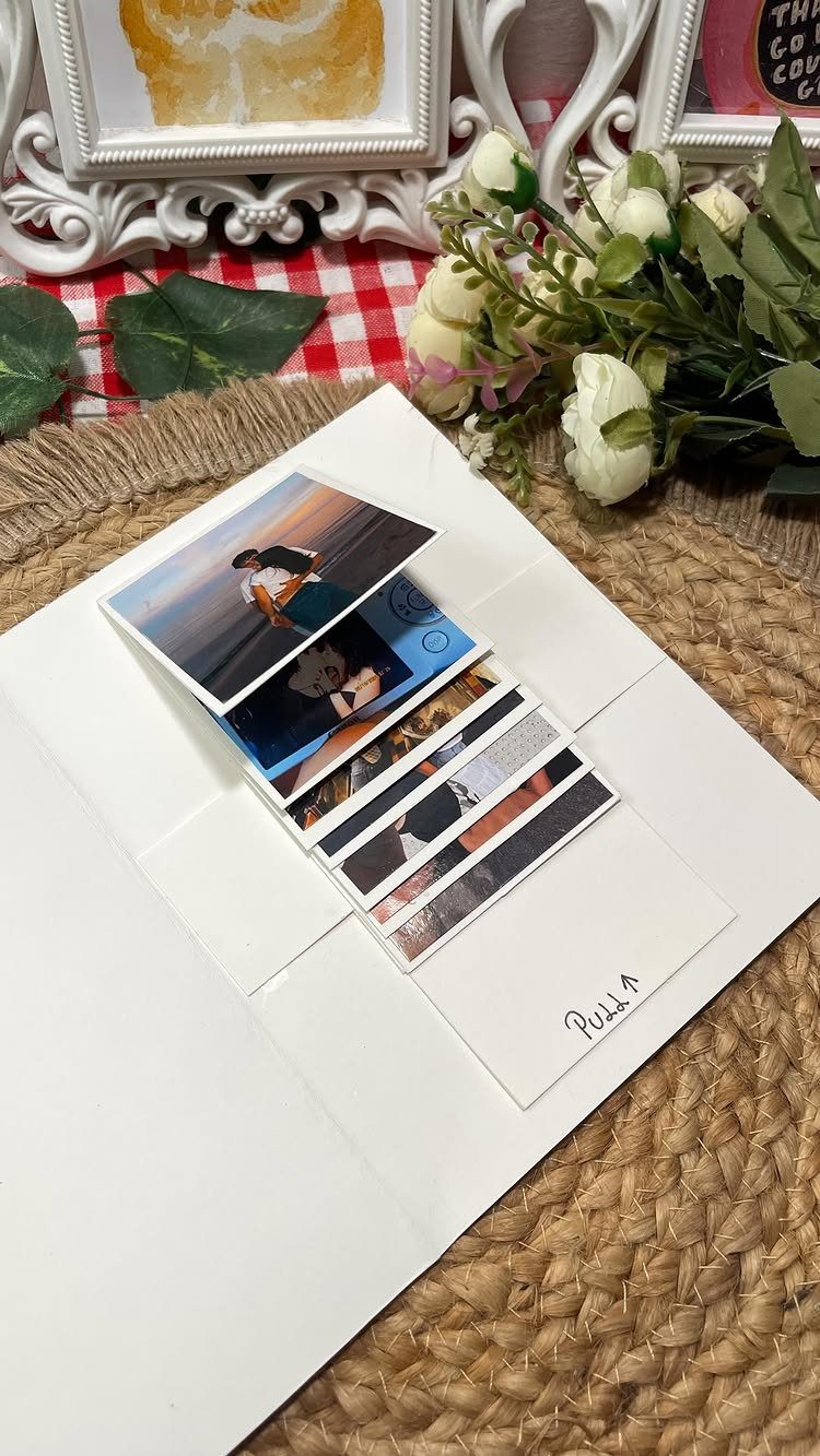 Handmade pull-out photo card showing a couple, placed on a woven mat with flowers.
