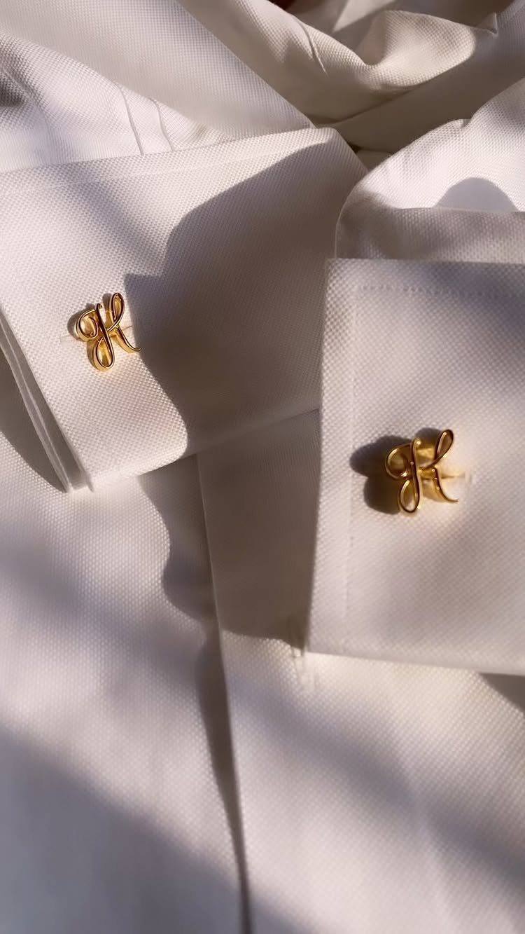 Gold bow-shaped cufflinks fastened to the cuffs of a white dress shirt.