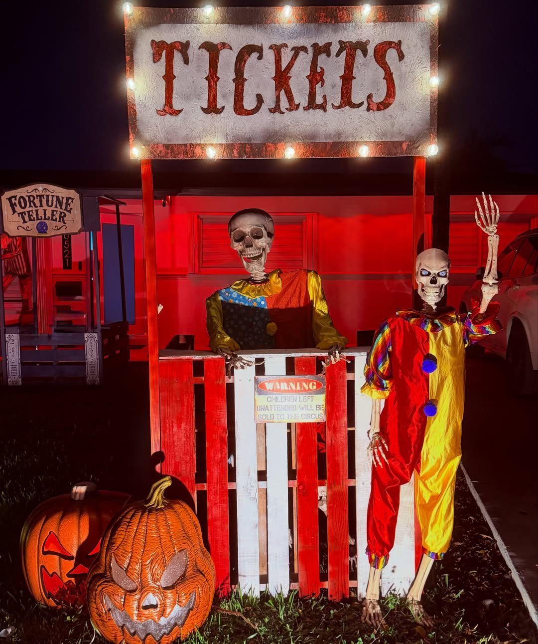 Carnival ticket booth with skeleton clowns and pumpkins for a spooky trunk or treat.