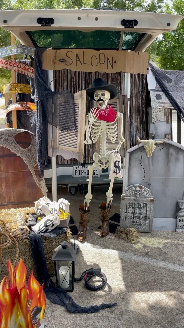 Skeleton cowboy sitting in front of a western saloon themed trunk or treat display