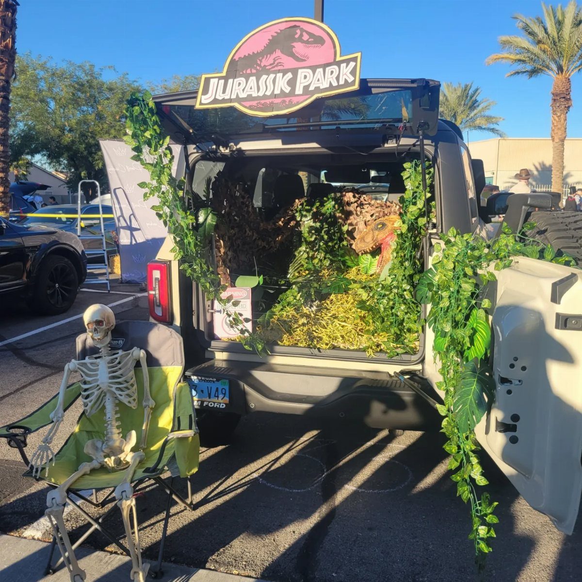 Jurassic Park themed car trunk decoration with a skeleton sitting in a chair.