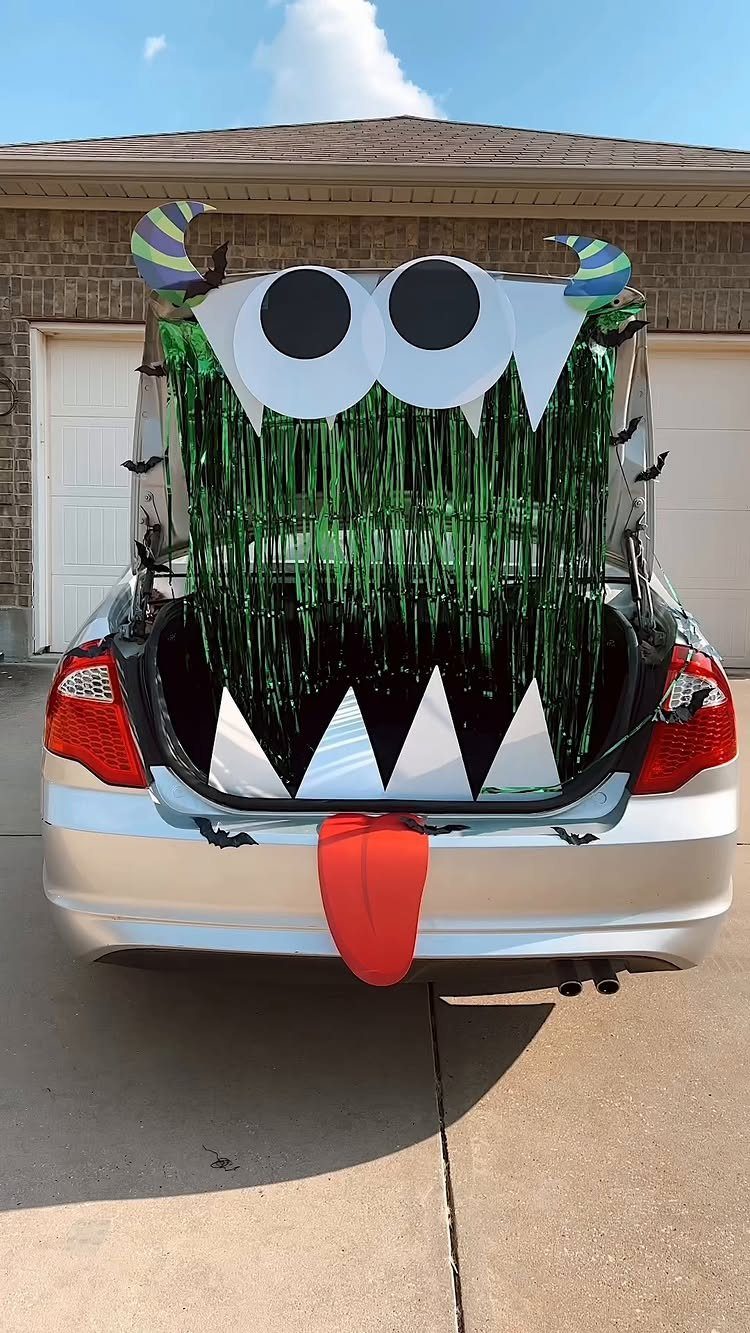 Silver car trunk decorated as a green monster with large eyes and red tongue.