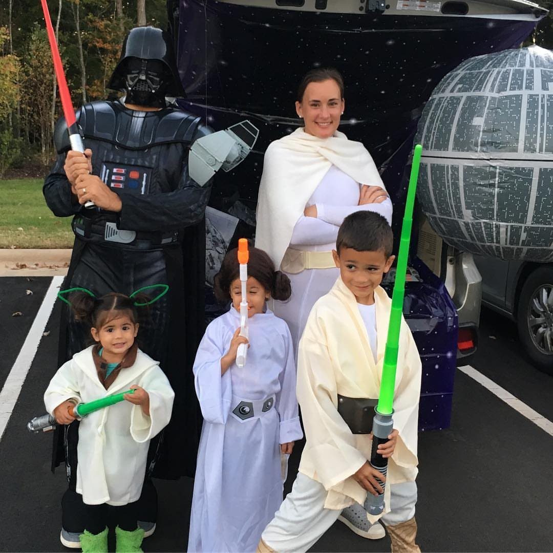 Family in Star Wars costumes posing by a space-themed car trunk with Death Star.
