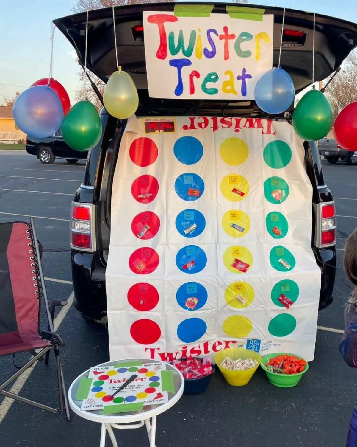 Twister Treat themed car trunk with colorful circles, balloons, and bowls of candy.