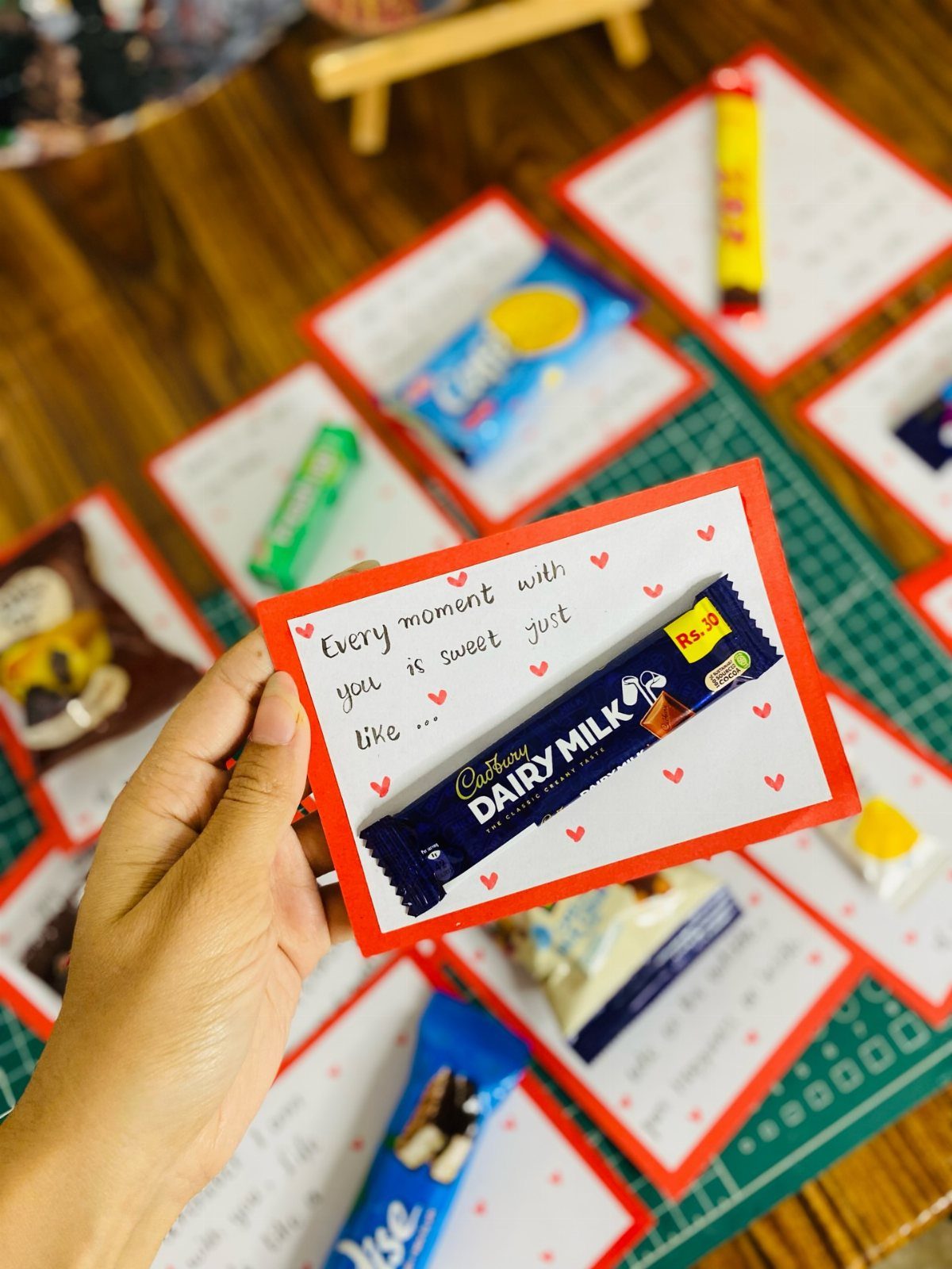 Hand holding a handmade Valentine's card with a chocolate bar and romantic text.