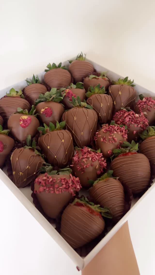 Chocolate-dipped strawberries with drizzles and pink sprinkles in a white gift box.