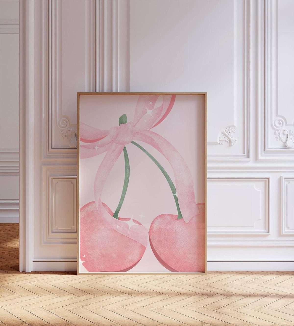 Framed art of pink heart cherries with a ribbon leaning against a white wall