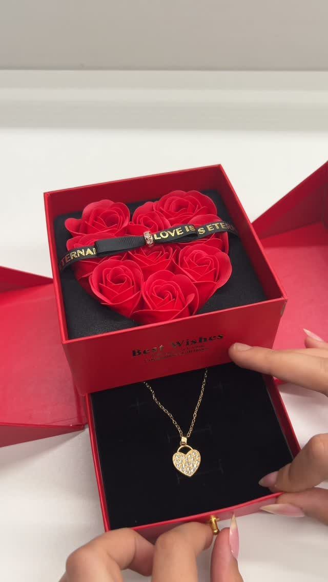 Gold heart pendant necklace and bracelet resting on red roses in a red box