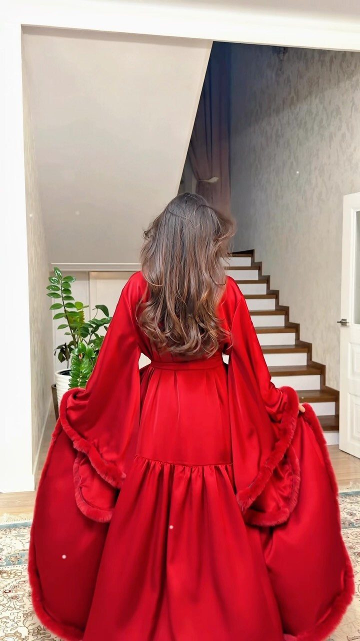 Woman from behind wearing a long red velvet luxury robe in a home.