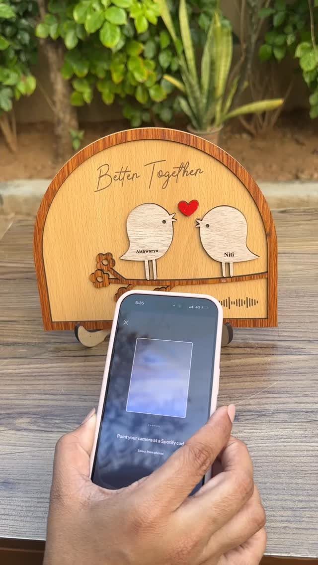 Wooden plaque with two birds and 'Better Together' text being scanned by smartphone