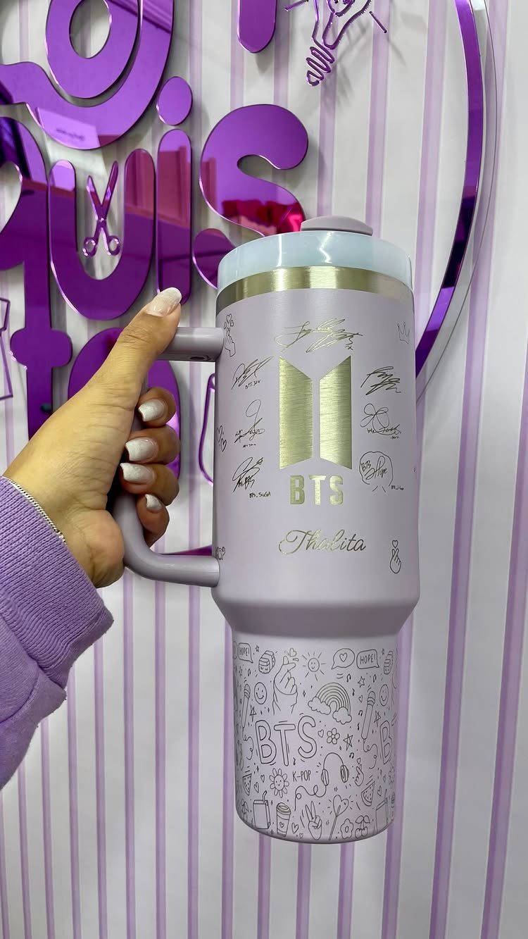 Purple personalized travel mug with BTS logo and name held by a hand.
