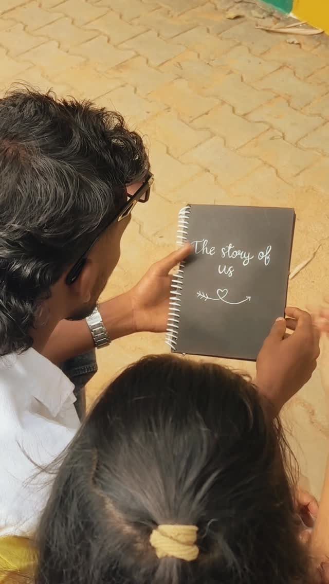Couple holding a black notebook titled The story of us outdoors.