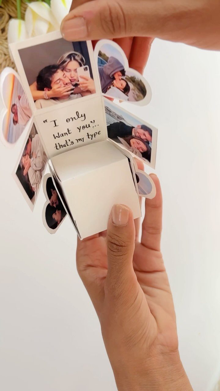 Small white explosion box with couple photos and a romantic handwritten note.