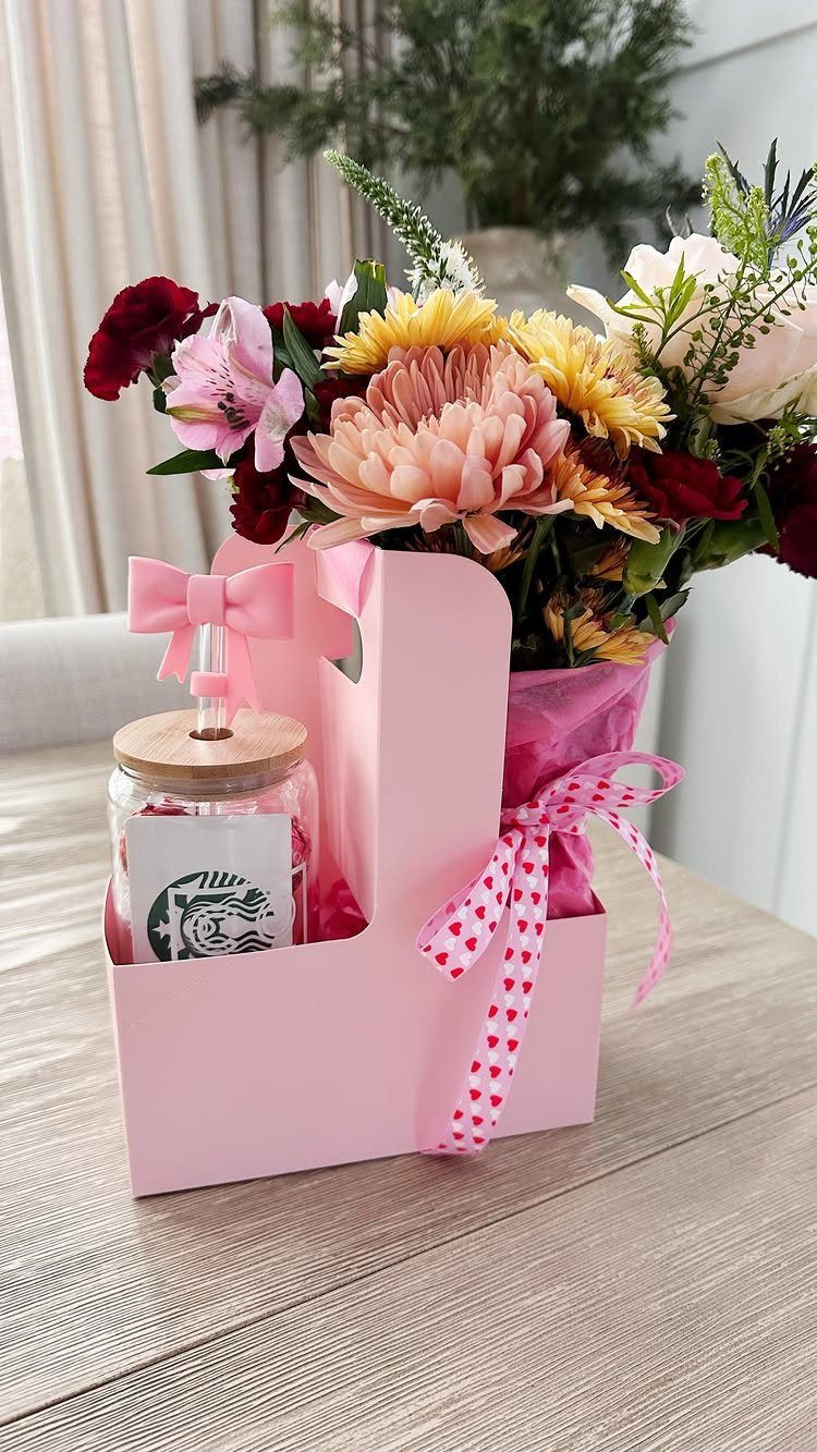 Pink gift carrier with a colorful flower bouquet and a small glass jar.