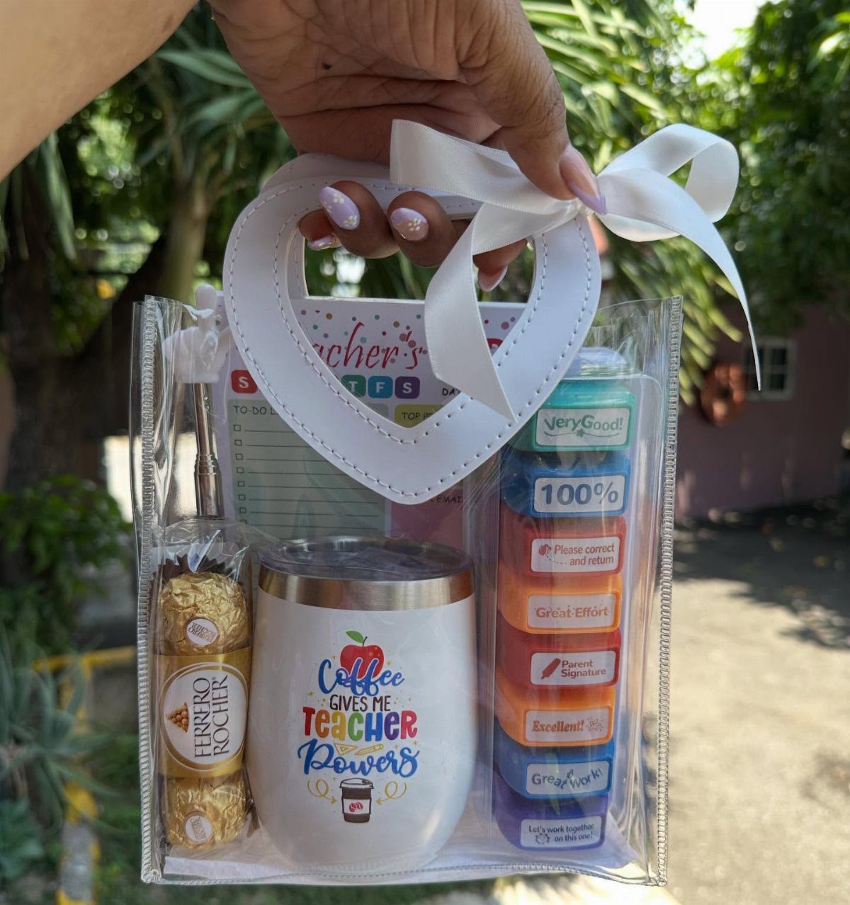 White teacher tumbler and chocolates inside a clear gift bag with white ribbon.