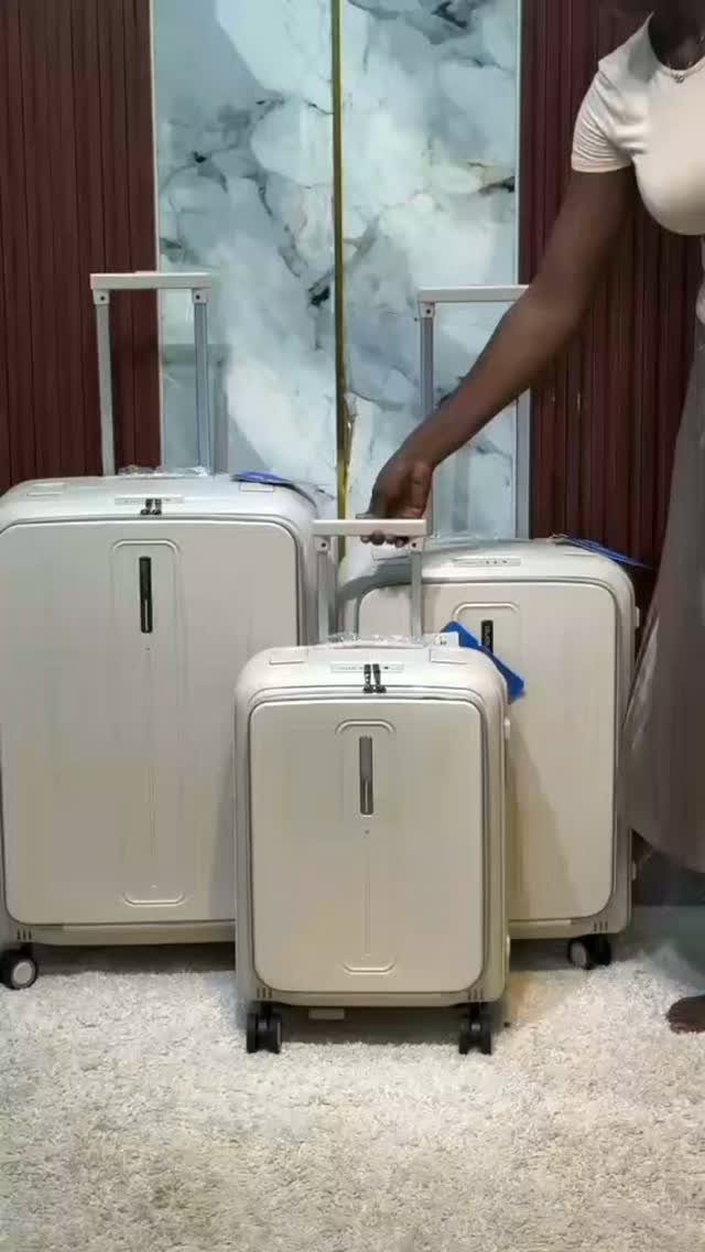 Three cream-colored hardshell suitcases of different sizes on a white shag carpet.