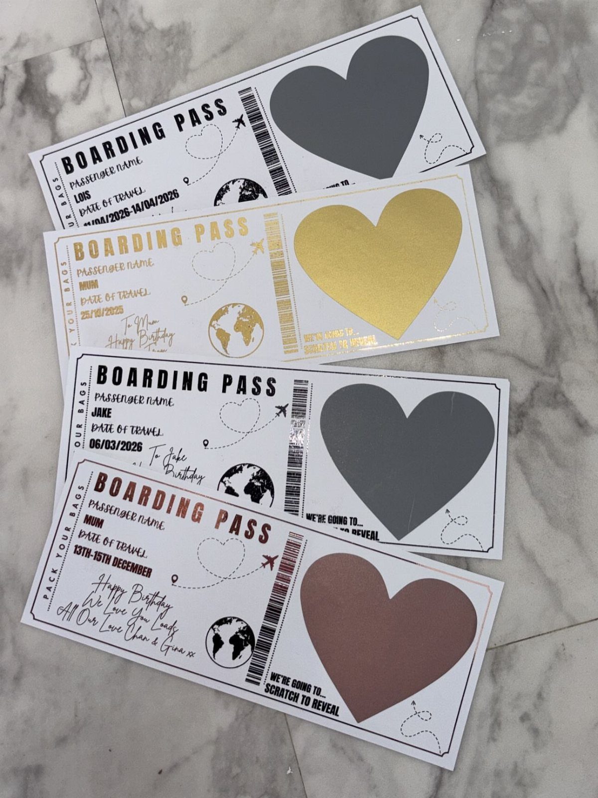 Custom boarding pass gift vouchers with scratch-off hearts on a marble background.