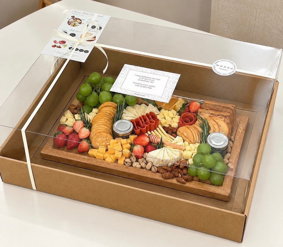 Gourmet charcuterie board with fruits, cheeses, and crackers in a gift box