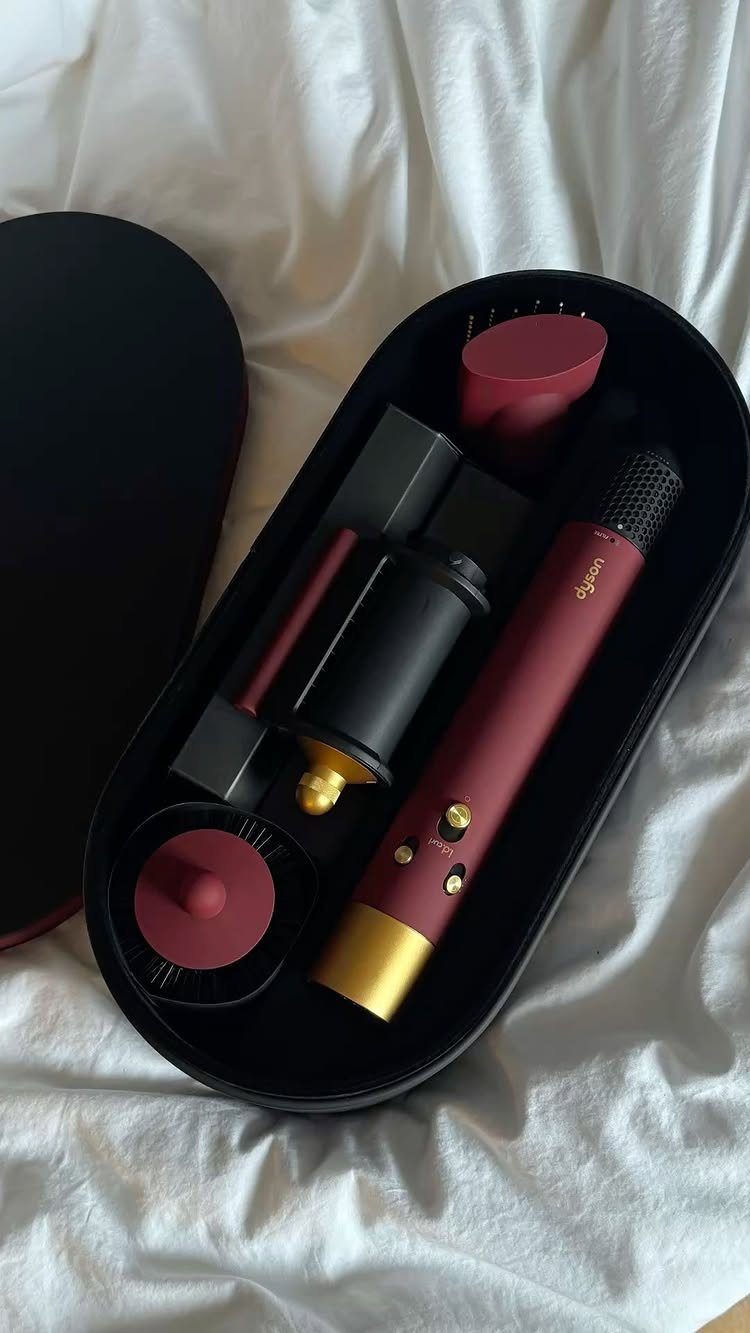 Burgundy and gold Dyson Airwrap hair styler set in a black storage case