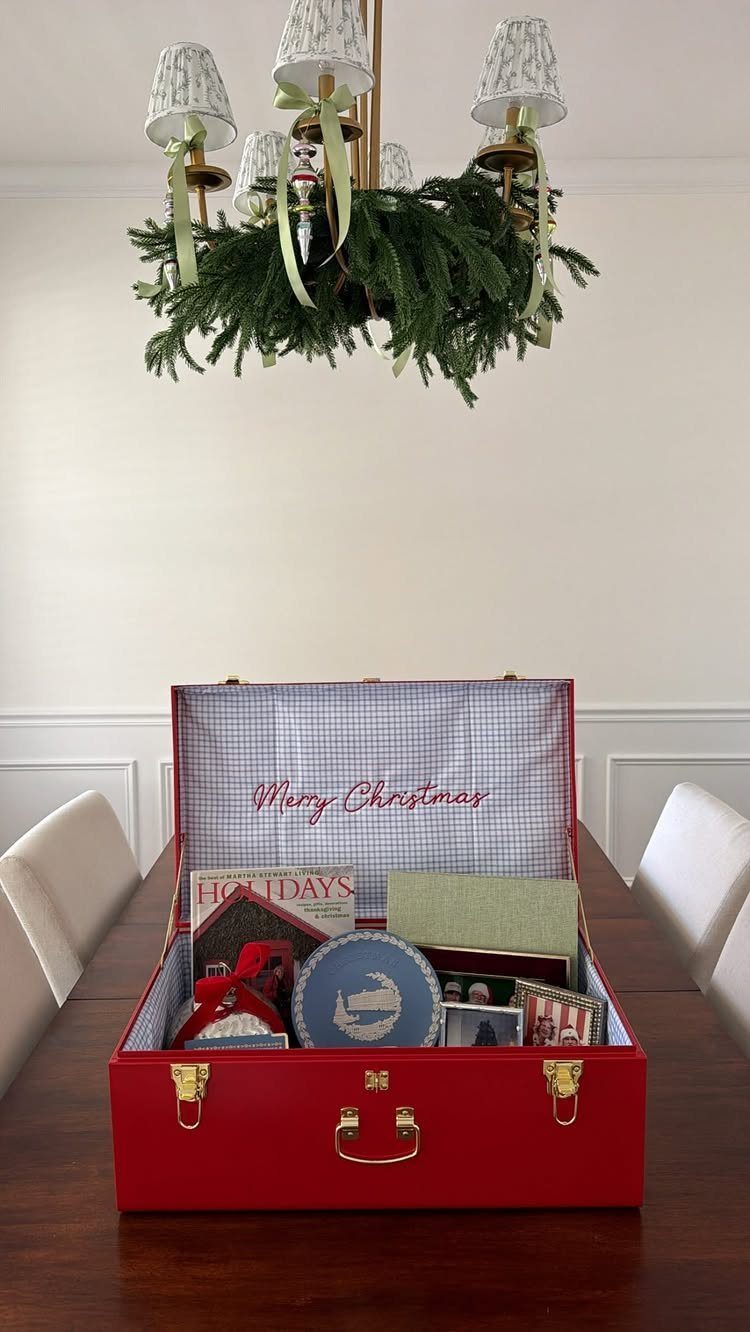 Red suitcase gift box filled with holiday presents on a wooden dining table