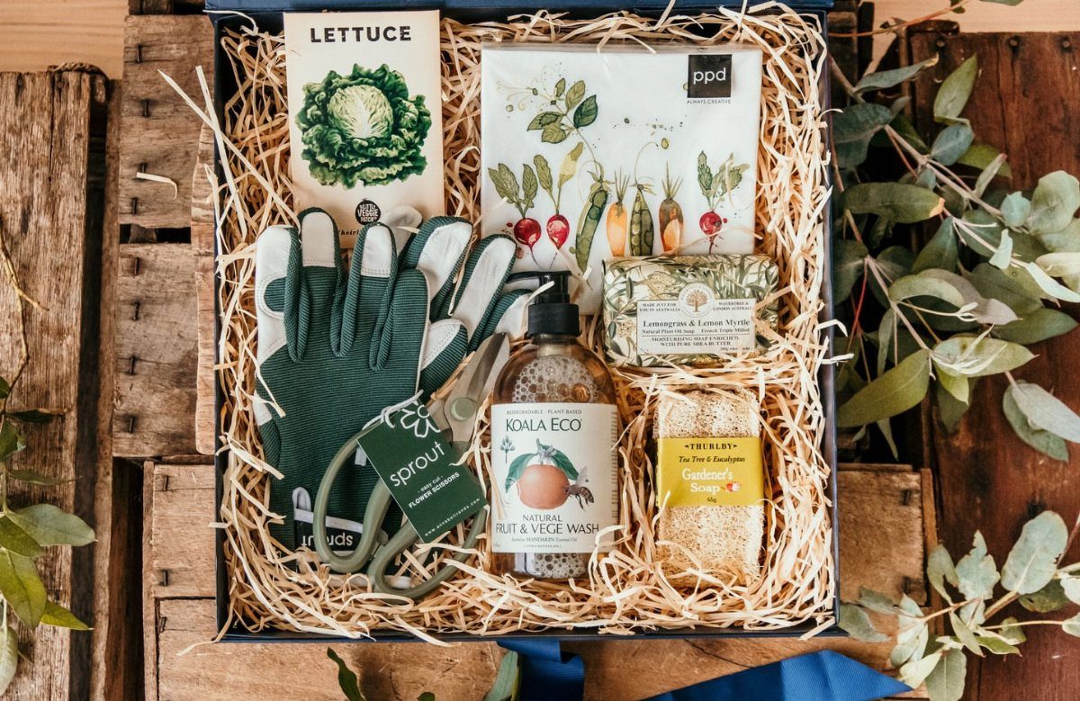 Gardening gift kit with seeds, gloves, shears, and soap in a straw-filled box.