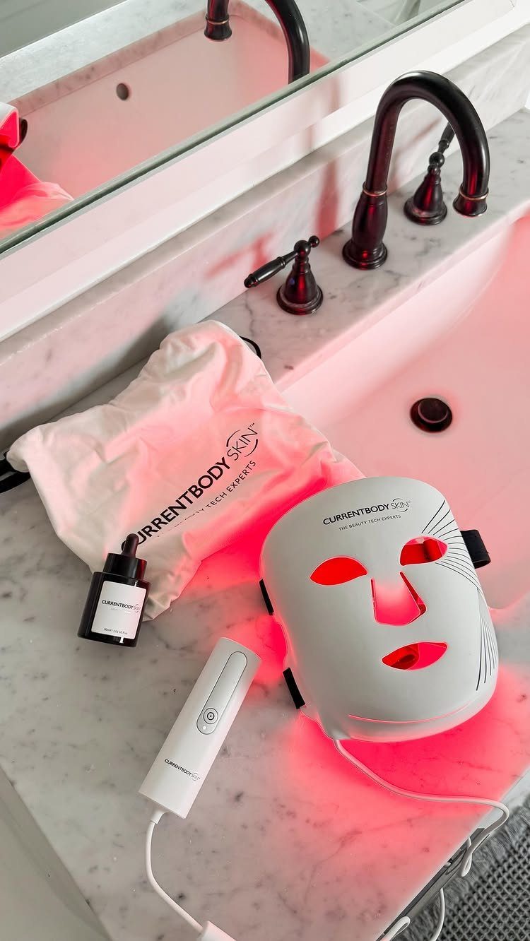 White LED face mask emitting red light on a marble bathroom counter