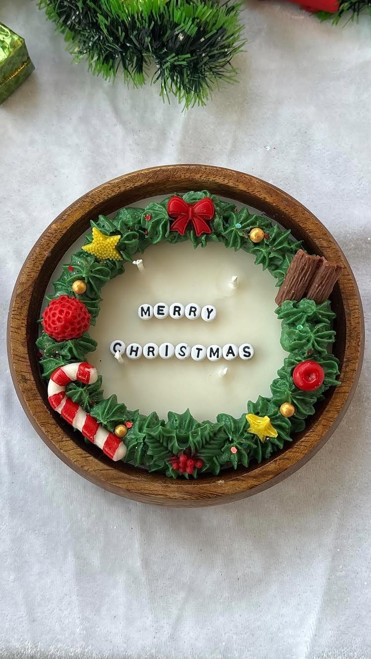 Christmas themed candle in a wooden bowl with a decorative green wreath
