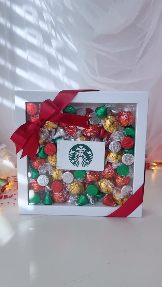 White shadow box filled with colorful wrapped chocolates and a Starbucks gift card.